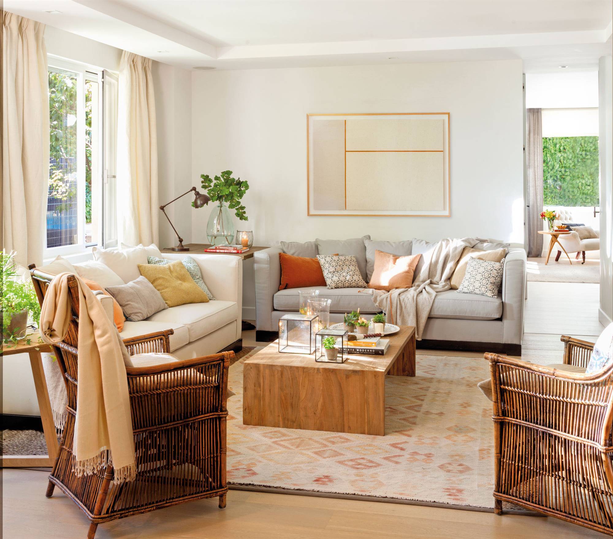 Salón con un sofá blanco, otro gris y mesa de centro de madera. 