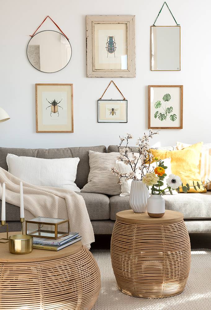 Salón con una composición de cuadros y espejos en la pared del sofá. 