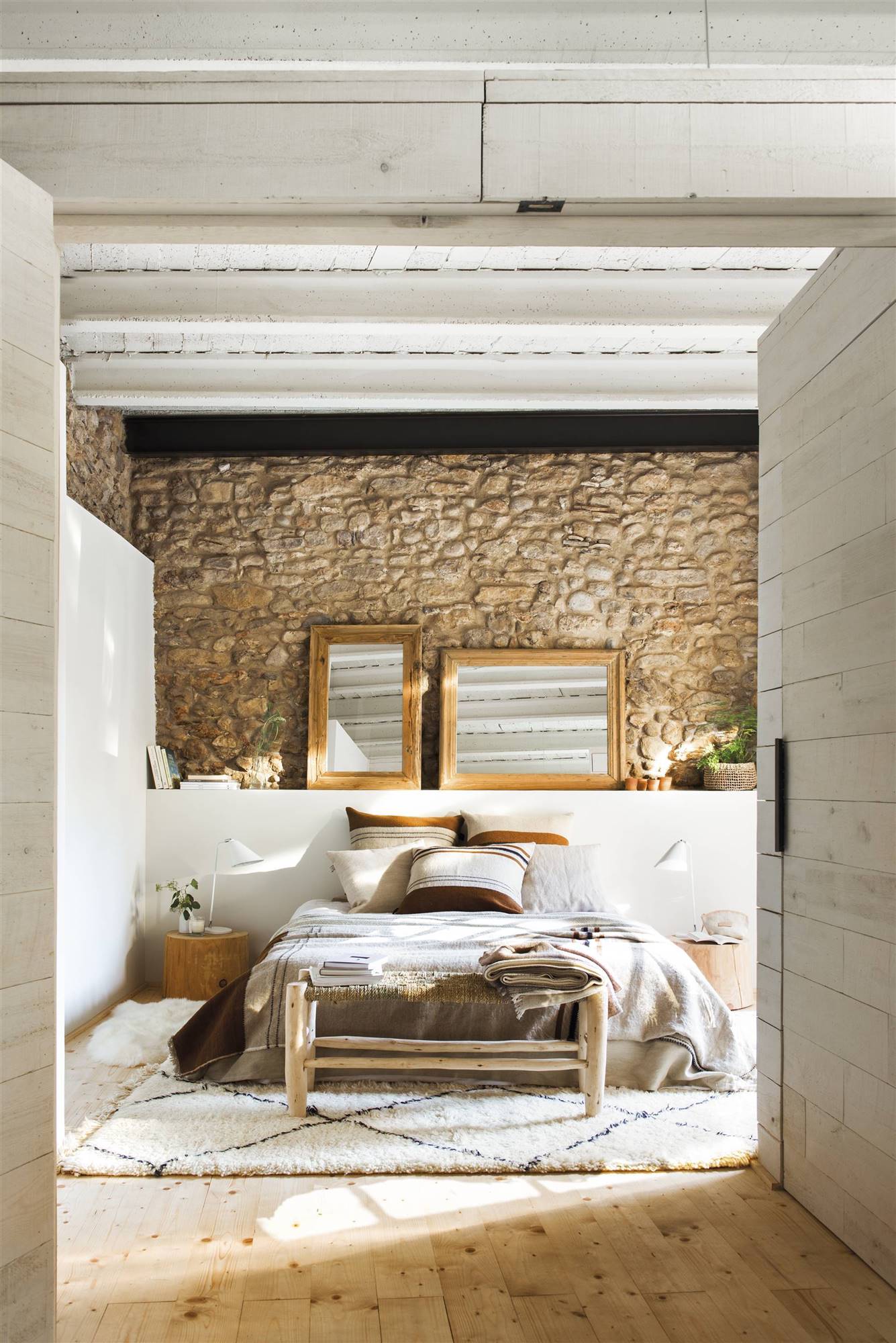 Dormitorio de estilo rústico con dos espejos sobre el cabecero