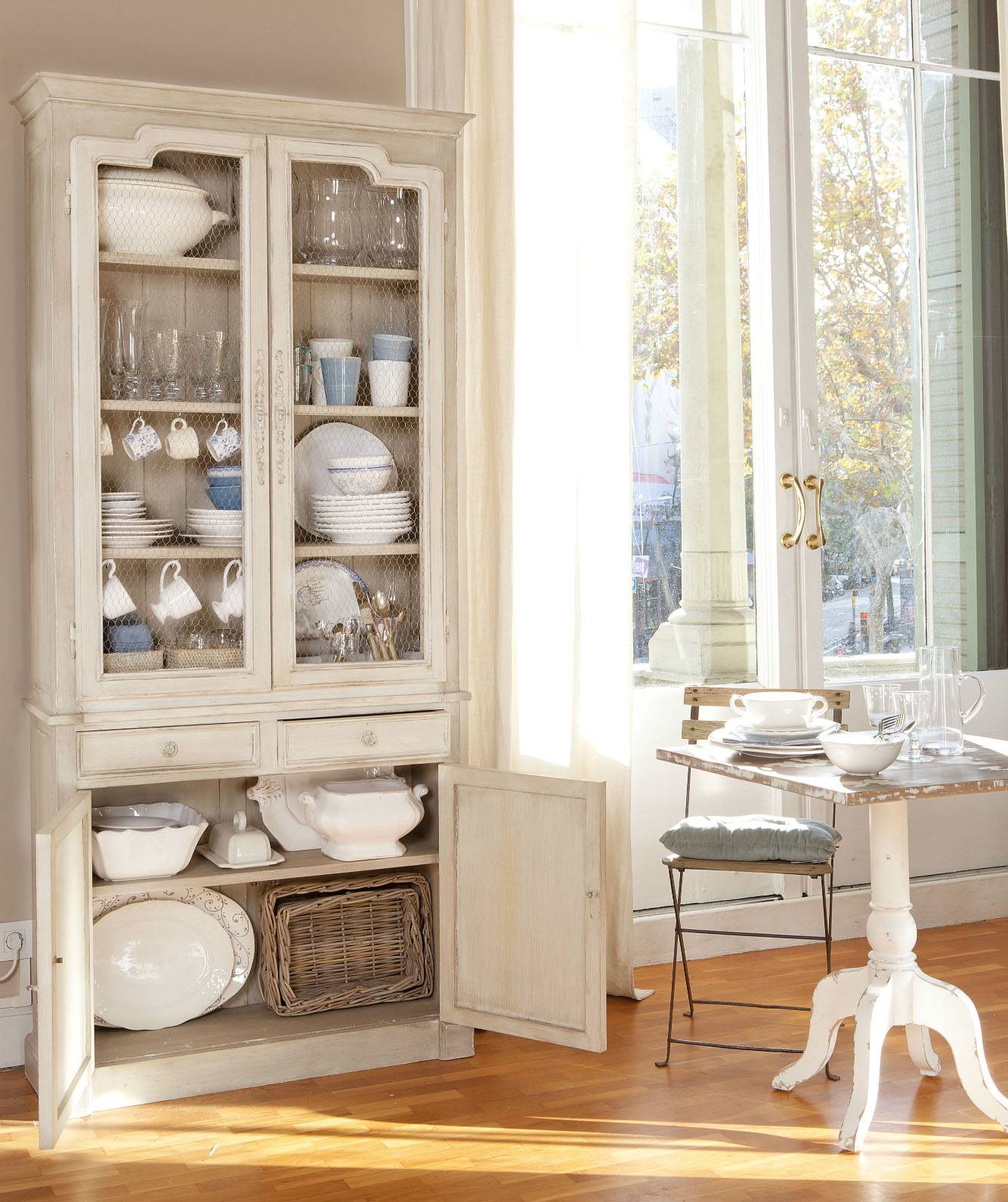 Vajillero de madera recuperado decapado en blanco con puertas con rejilla de gallinero junto a mesita con sillas plegables 332852