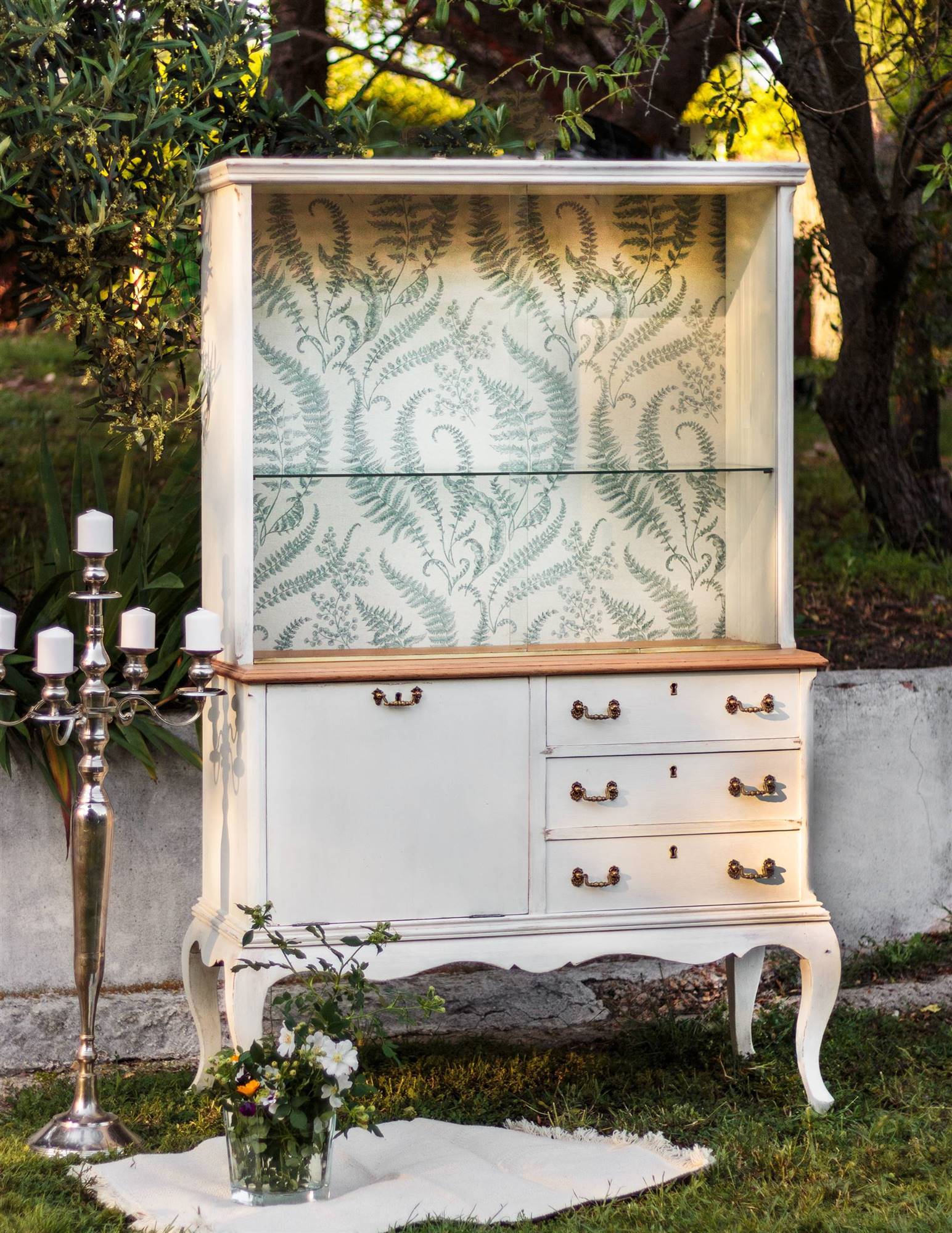 Vitrina restaurada pintada en blanco y decorada con una tela con motivos vegetales