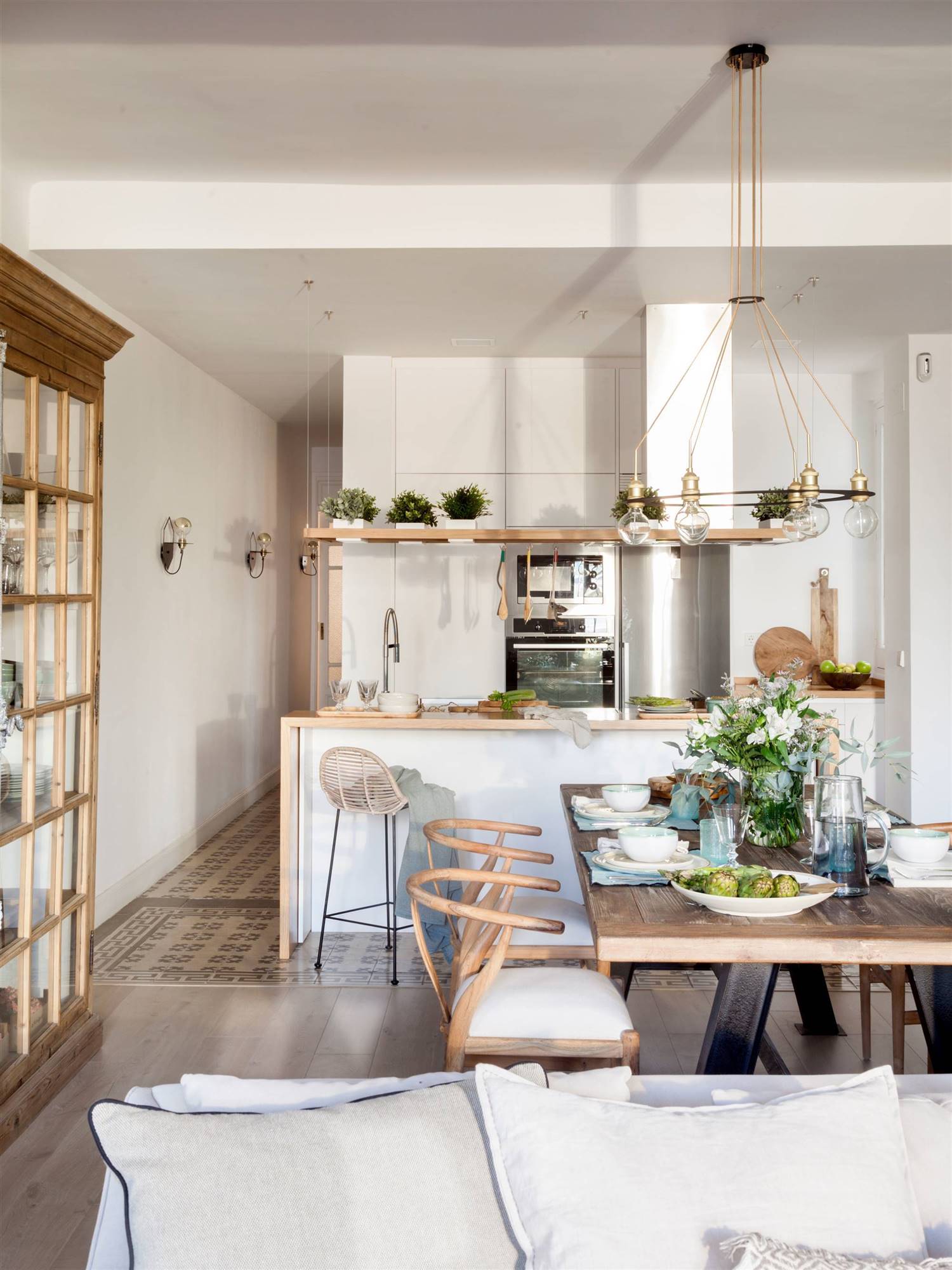 Cocina abierta al comedor con isla y muebles blancos y en madera.