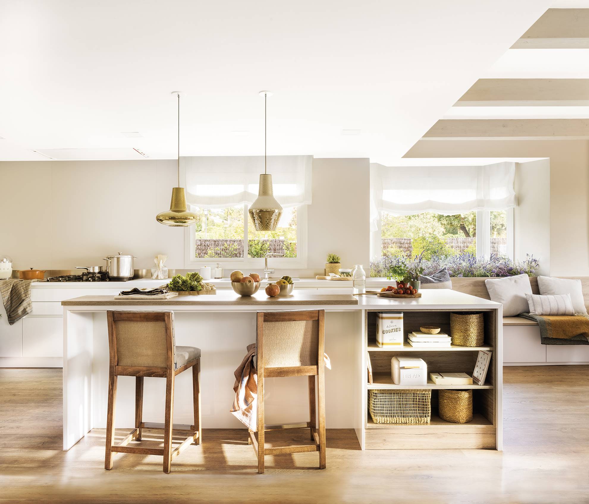 Cocina abierta con una gran isla y taburetes de madera. 