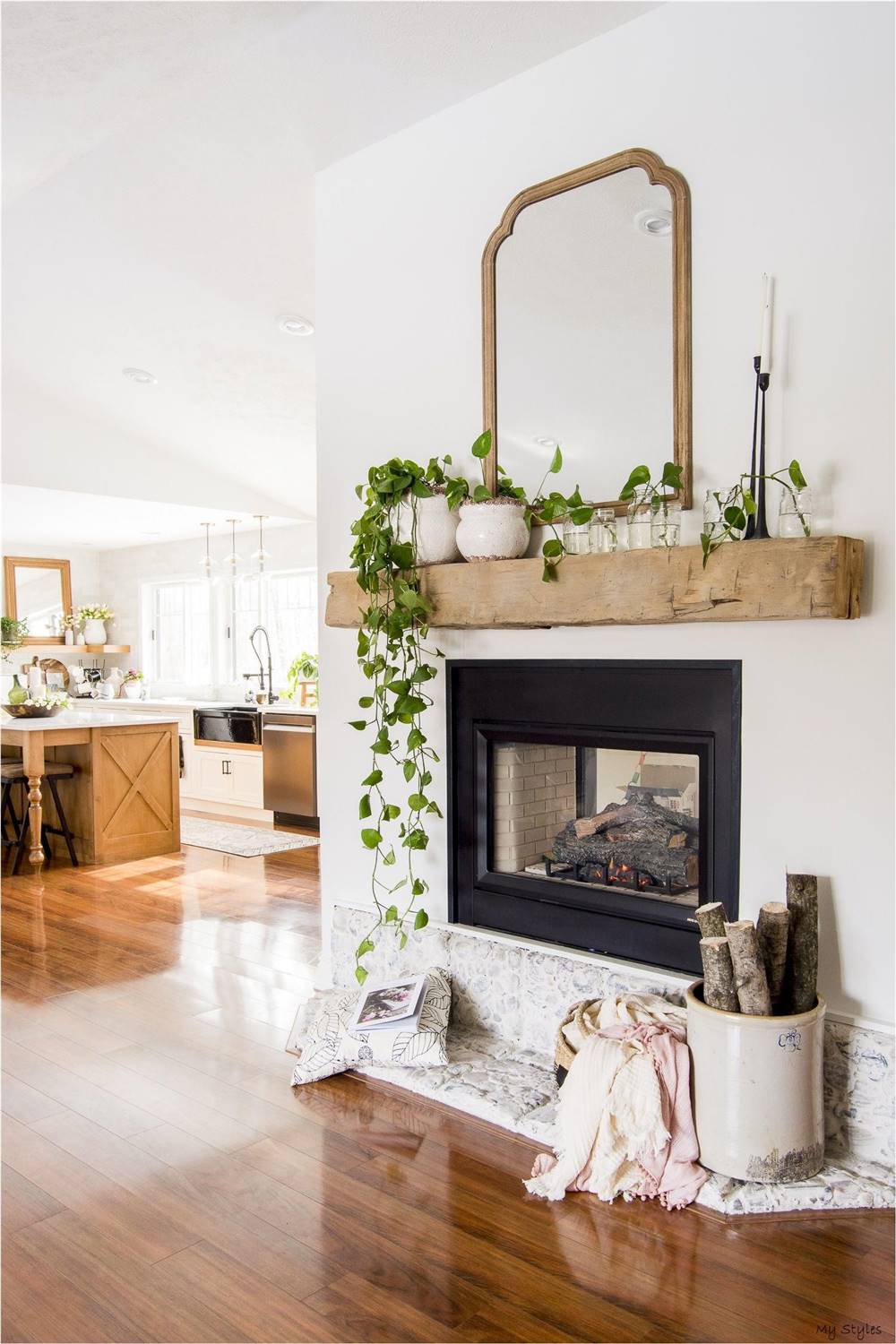 Chimenea decorada con una repisa de madera con plantas colgantes y un espejo de madera