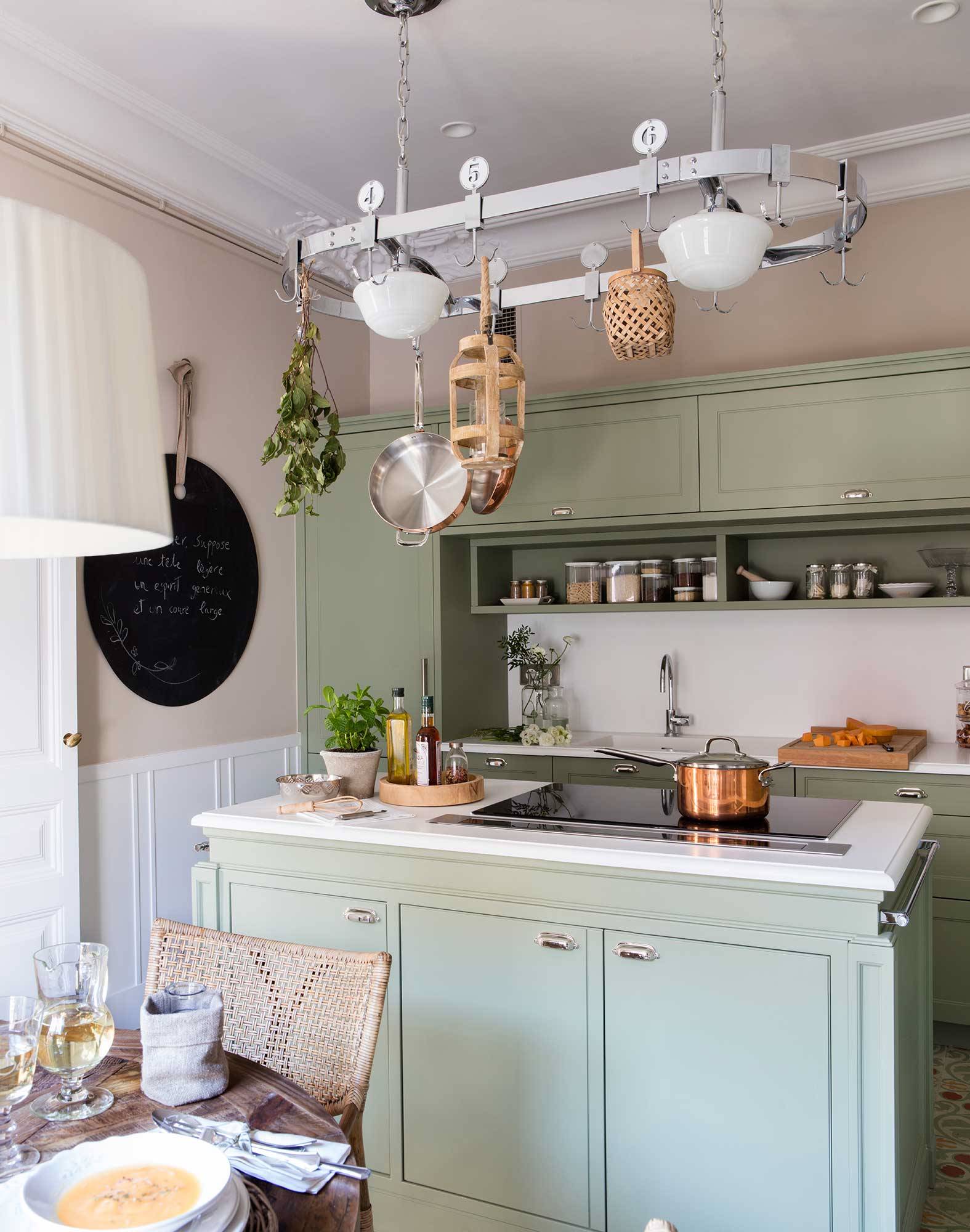 Cocina en verde con isla y paredes con molduras. 