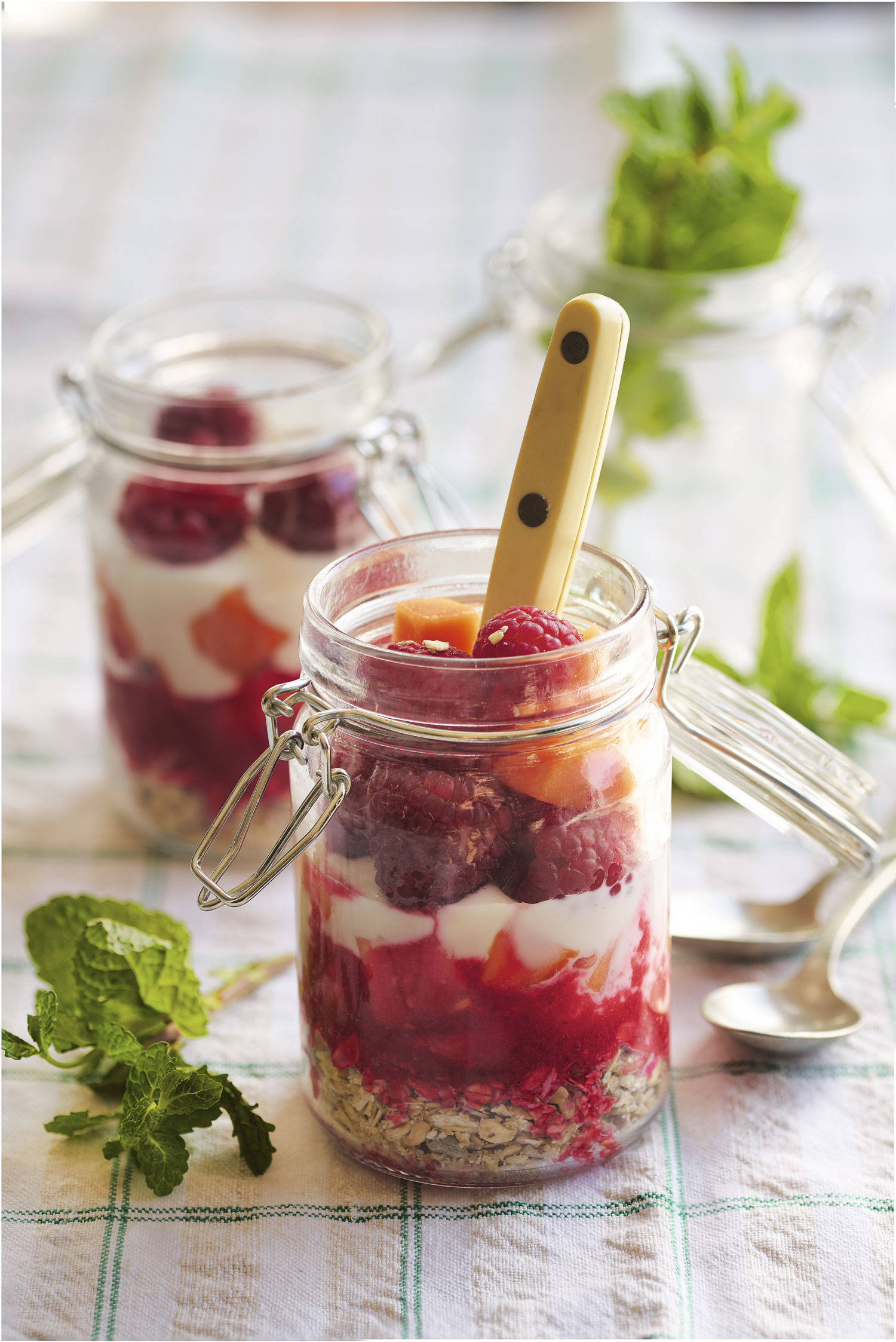 Vasitos de avena con yogur de soja, frambuesas y avellanas.