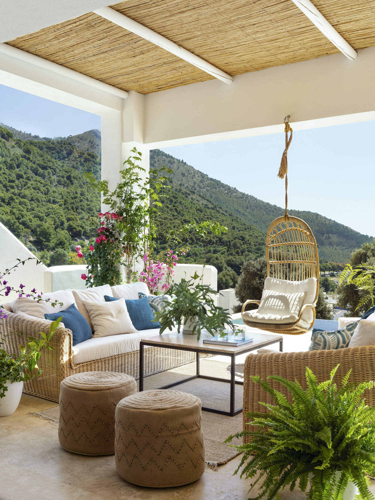 Terraza con muebles de mimbre y blancos.