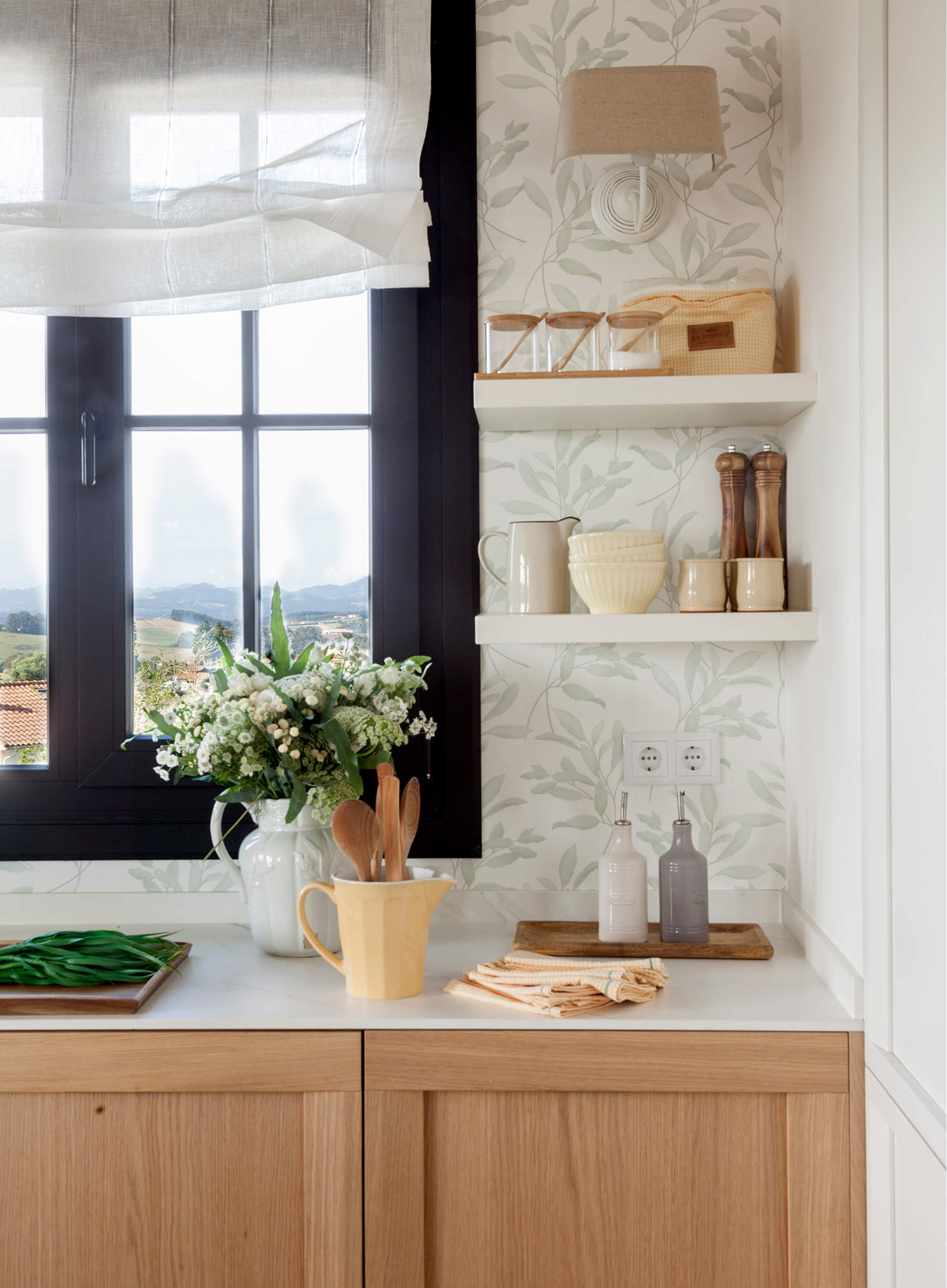 Rincón de desayuno en la cocina con estantes en blanco junto a la ventana