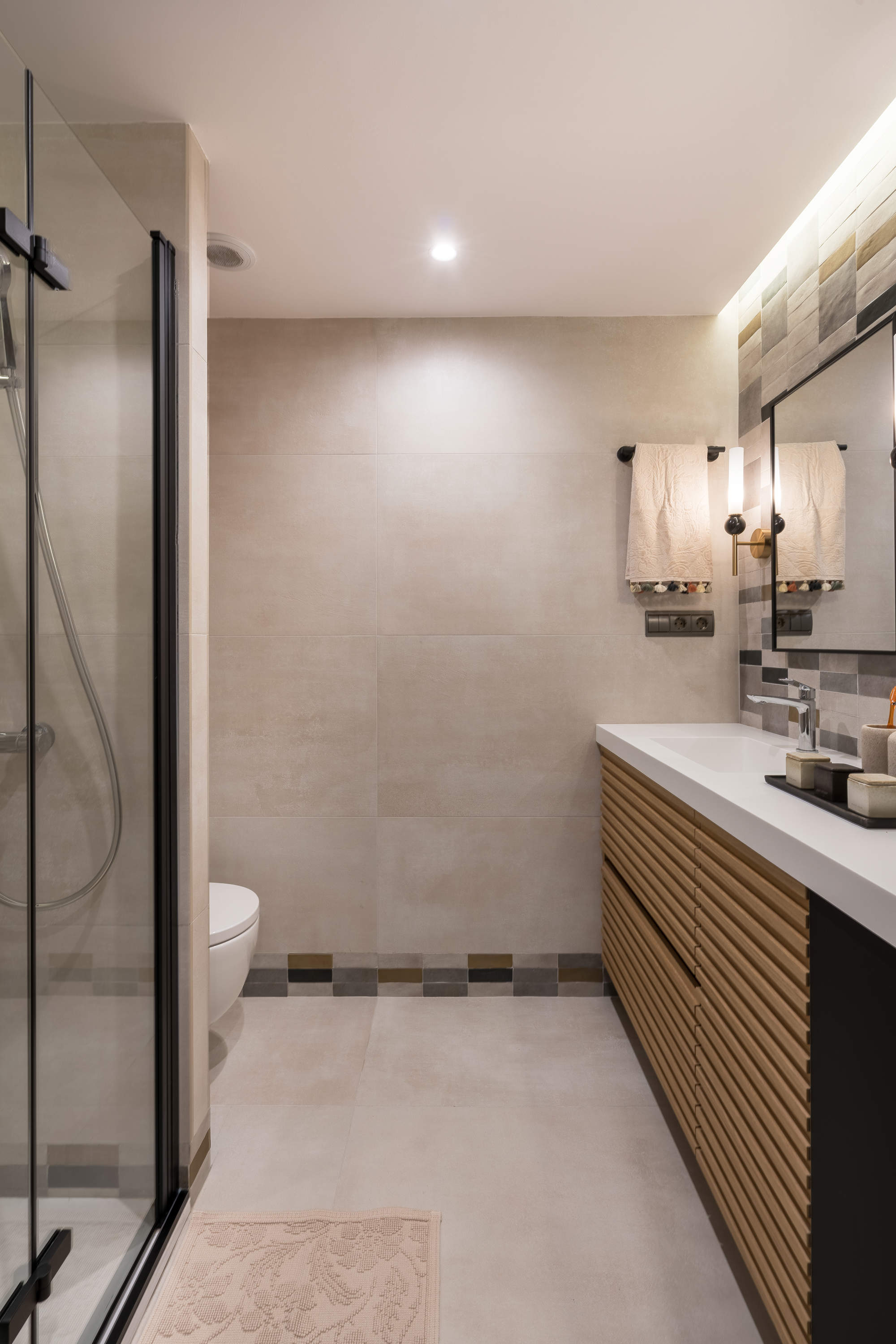 Baño con mueble de madera, tonos neutros y ducha con mampara con perfilería negra