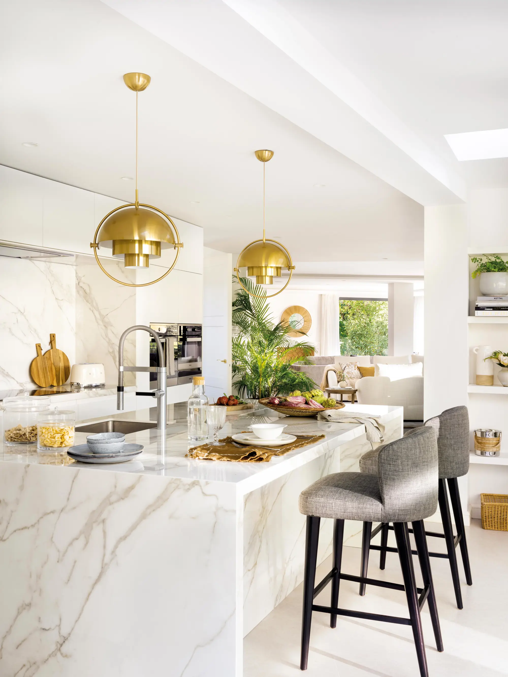 Cocina blanca abierta al salón con isla y detalles dorados
